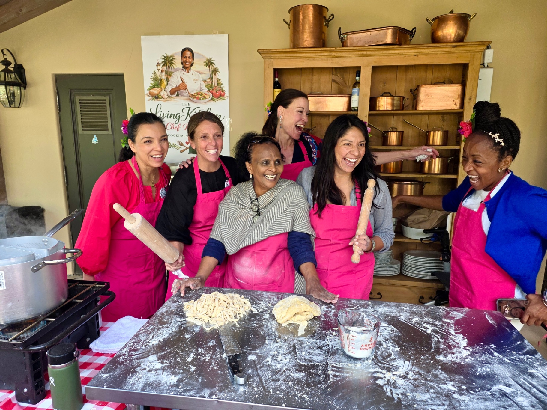 Women in pink aprons making pasta in a cooking class
